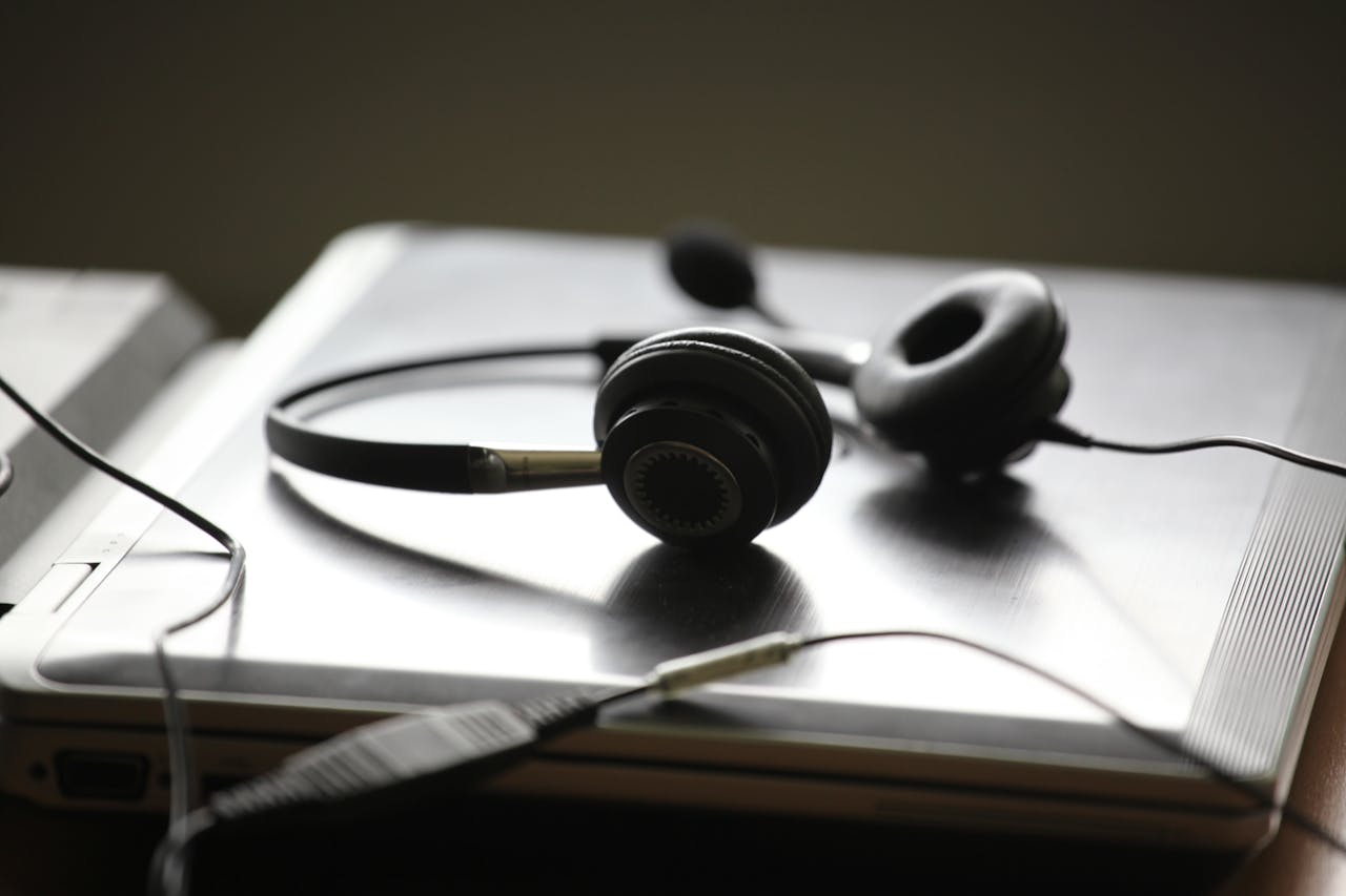 why-choose-us Black headphones lying on a closed silver laptop, symbolizing remote work or digital communication.