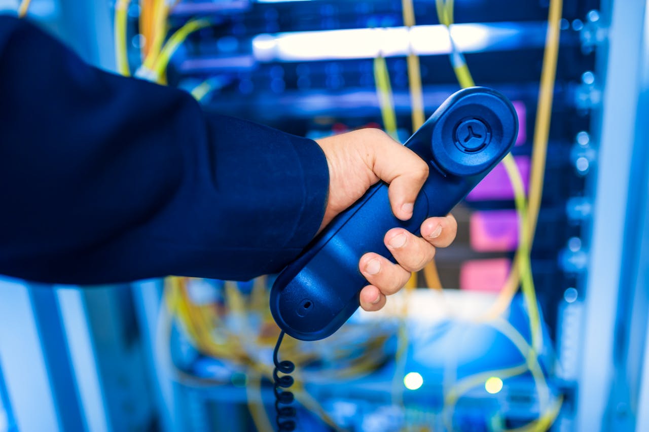 our-experience Close-up of a hand holding a telephone receiver in a server room emphasizing technology.