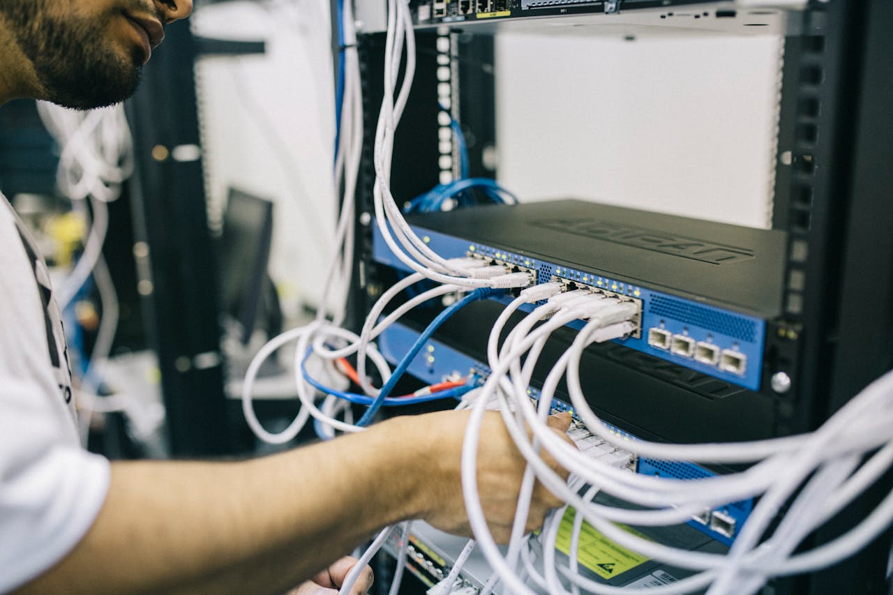 about-01 An IT professional configuring network cables in a server rack, focusing on Ethernet connections.