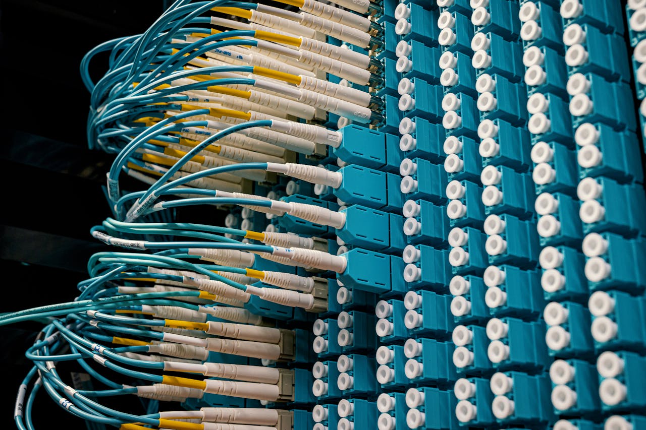 gallery-3 Detailed view of fiber optic patch cables connecting to a blue patch panel in a data center.